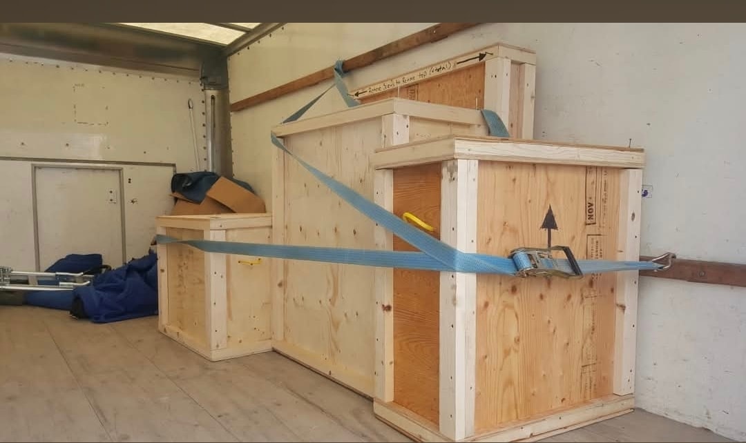 Wooden crates strapped and secured inside a moving truck for transport